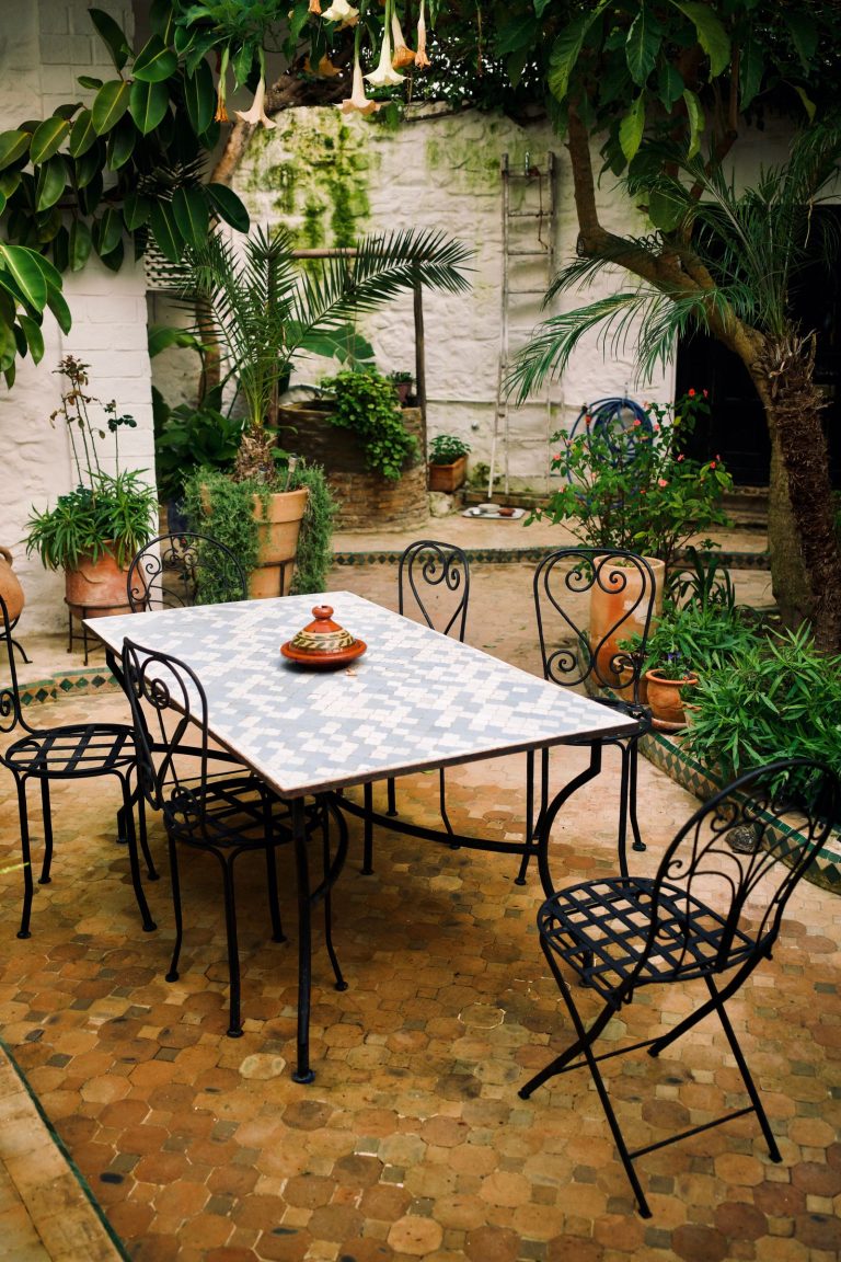 Mosaic-top table and wrought-iron chairs in a Moroccan riad garden