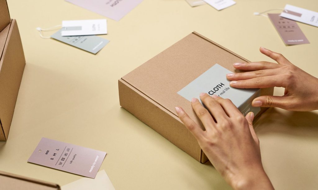 Own-brand label being applied to a kraft carton with hangtags laid out ready for retail